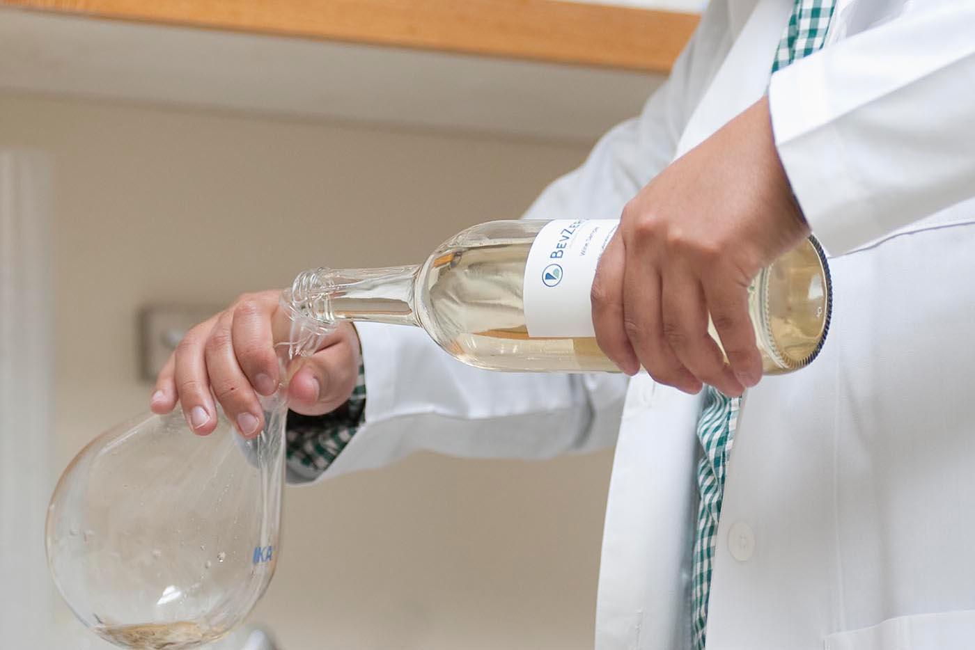 Scientist pouring BevZero white wine for non-alcoholic beverage product development and alcohol removal