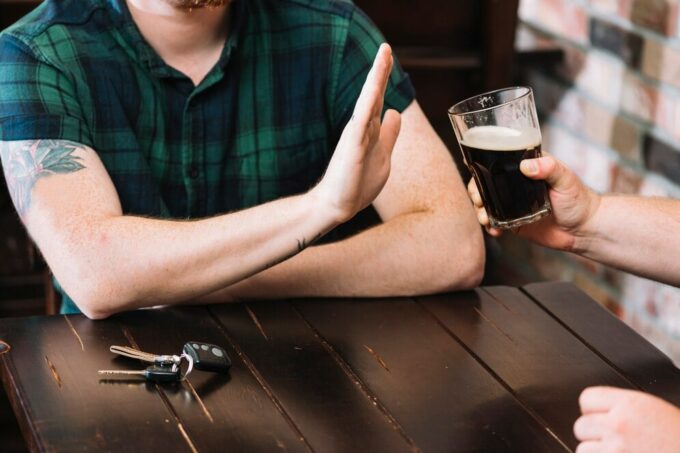 man hold hand up to drink being offered