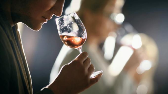 A man smells a glass of light-colored wine during a wine tasting.