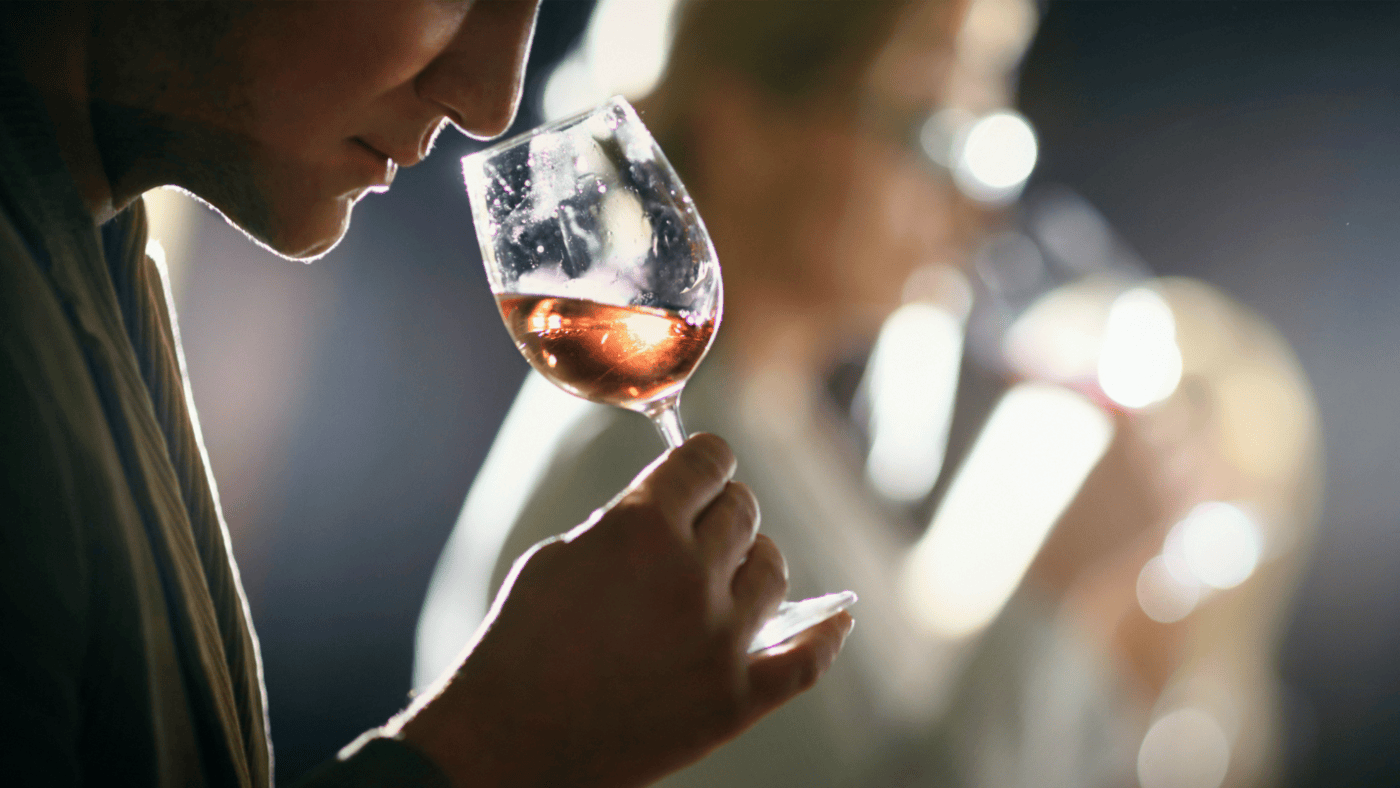 A man smells a glass of light-colored wine during a wine tasting.