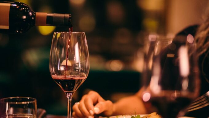 A glass of wine is being poured at a dinner table.