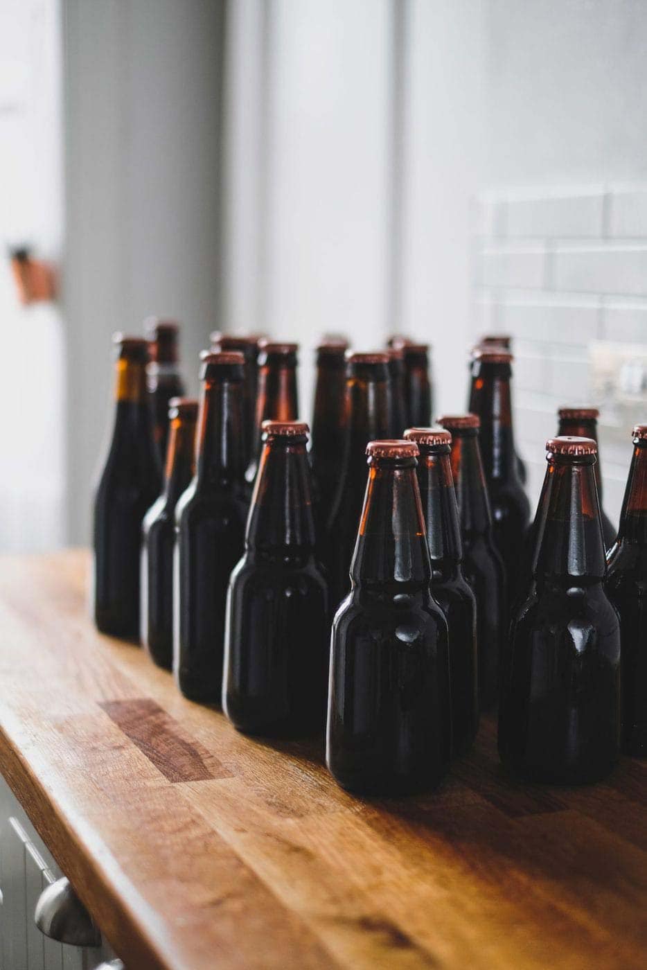 Glass beverage bottles on a wooden shelf, showcasing non-alcoholic beverage solutions.