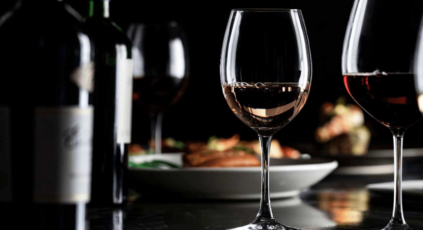 Side-lit wine glasses, bottles, and meal set for beverage specialists and innovators.