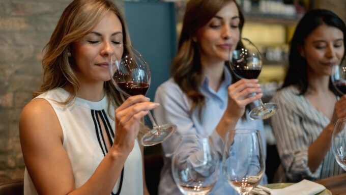 Three women in business attire tasting wine at a beverage industry event