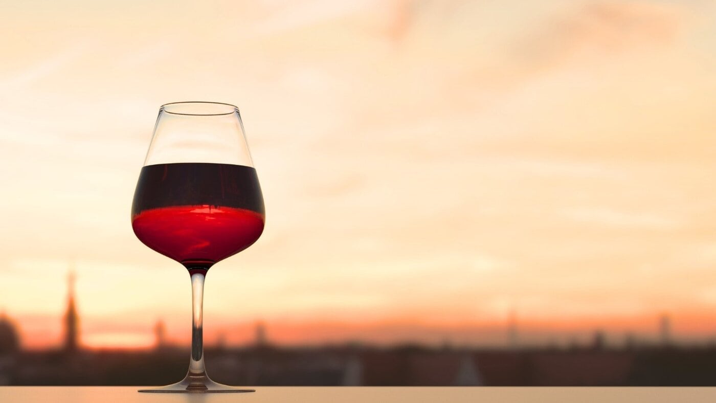Wine glass on windowsill with sunset, illustrating beverage industry lifestyle