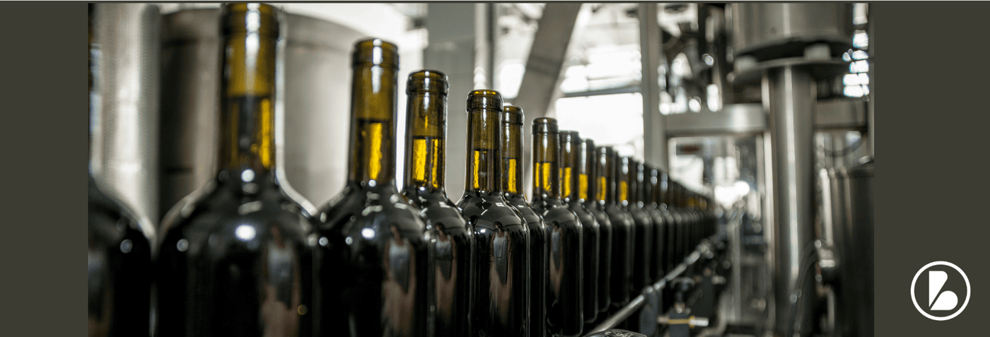 Wine bottles on an automated bottling line, illustrating beverage manufacturing and stability solutions.